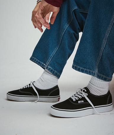 Close-up of black and white Authentic with blue jeans and white crew socks.