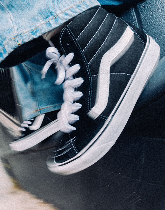 A blurry image of black and white Sk8-Hi paired with blue jeans.