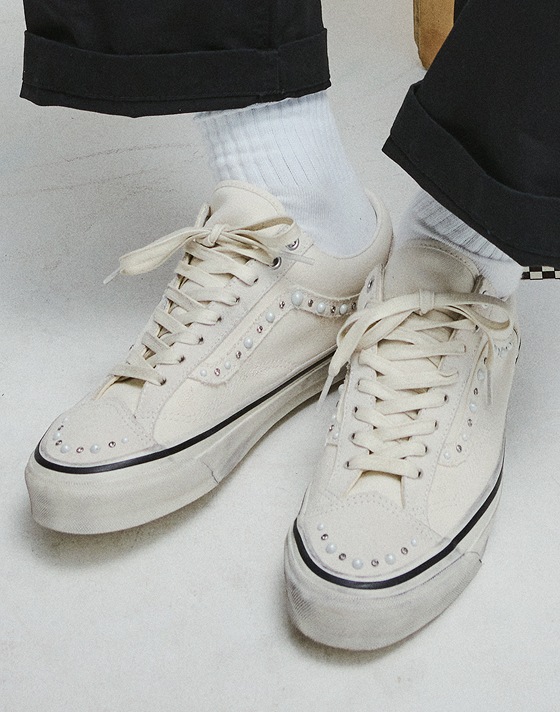 An overhead shot of someone wearing white Premium Old Skool 36 Pearlized shoes with white Vans crew socks.