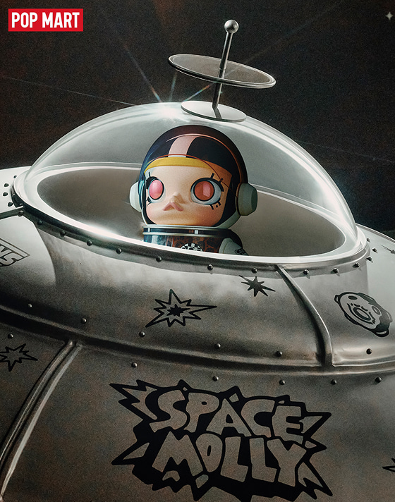 Space Molly sits in her UFO starship with light reflecting off the cockpit while a panel reads Space Molly.