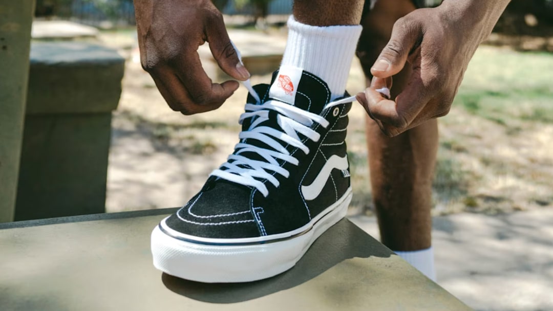 Someone lacing up a black Vans Sk8-Hi.