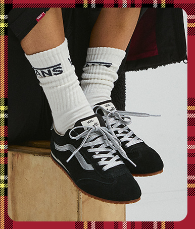 A plaid holiday border around an image of a young woman wearing black and silver Super Lowpro paired with white Vans crew socks.