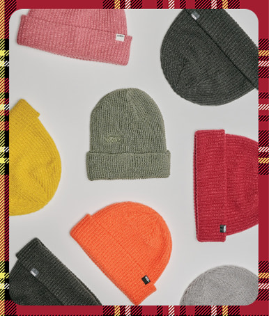 A plaid holiday border around an image of a variety of Vans beanies in different colors on the floor of a photography studio.