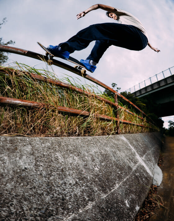 A young man grinds a rusty rail in a waterway wearing blue Skate Old Skool by 2 Riser Pads.