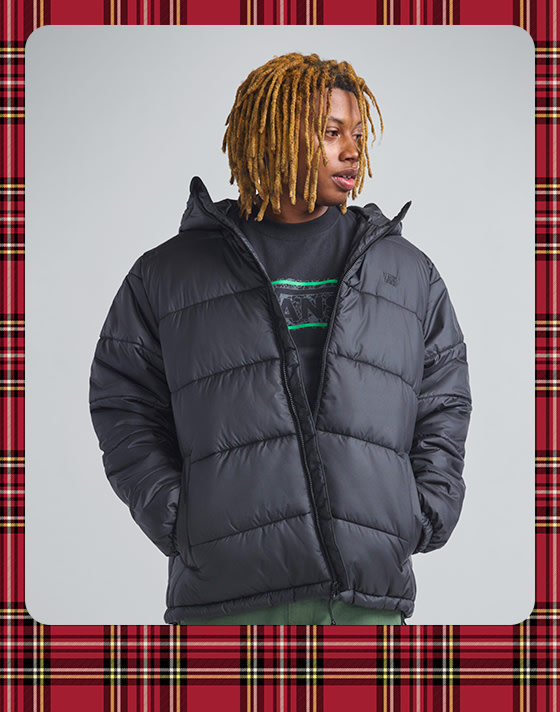 A photograph surrounded by a plaid holiday border of a young man wearing a deep twilight blue Skate Garage Reversible Jacket and chinos.