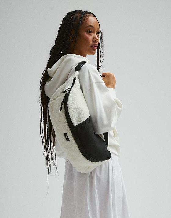 A young woman holds a marshmallow white Detached Sling Bag over her shoulder in a photography studio.