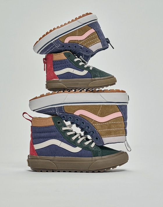 Two pairs of blue and green Kids Sk8-Hi Water Resistant Gum Shoe stacked on top of each other in a photography studio.