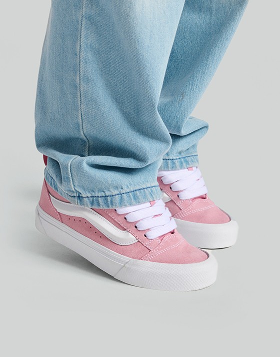 Close-up on pink and white Knu Skool paired with blue jeans in a photography studio.