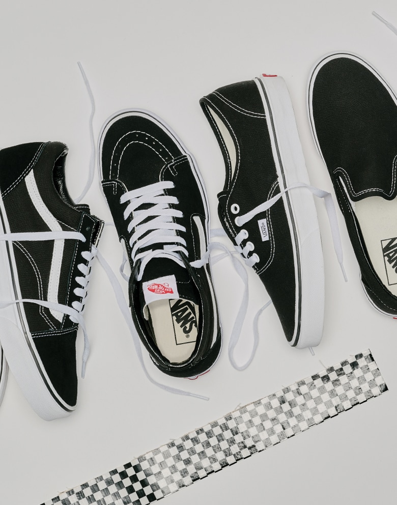 A black and white Old Skool, Sk8-Hi, Authentic, and Classic Slip-On lie on the floor together with their laces undone.