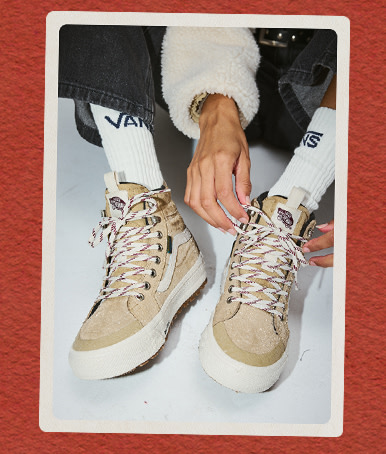 A pair of tan Sk8-Hi Waterproof Insulated shoes on a red holiday background.