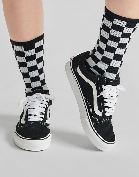 Close up shot from shin down of model wearing Checkerboard Crew Socks with black and white Old Skool shoes.