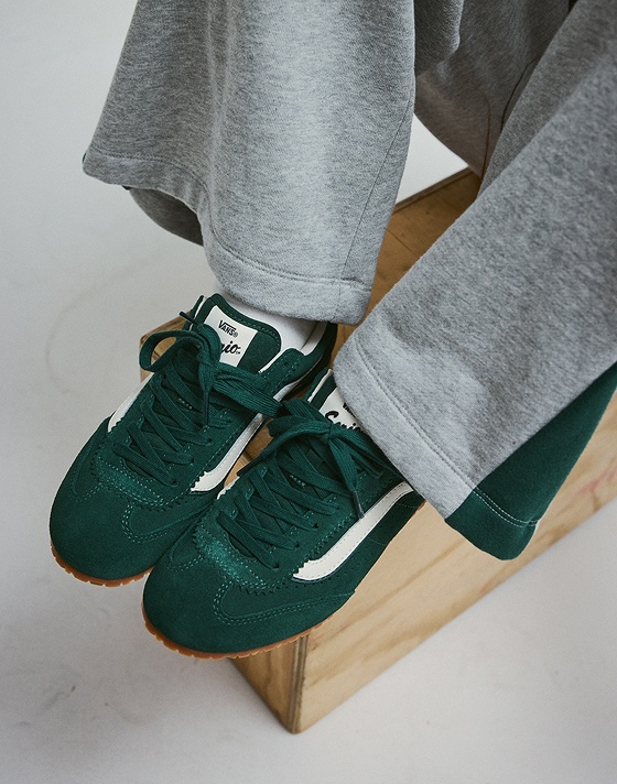Close-up of the adults' Vans Super Lowpro in the Emerald green color. The model also has on white socks and Rookie Track Sweatpants.