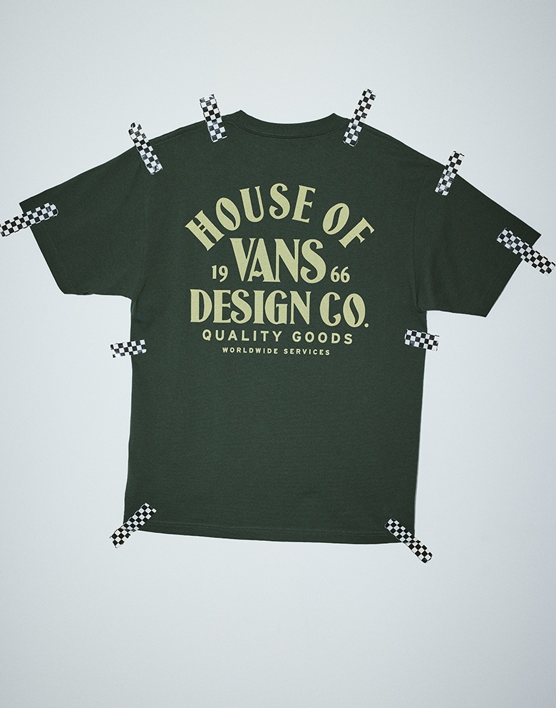 An image of a house of Vans Design Co tee with checkerboard tape pinning the shirt.