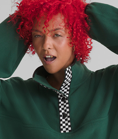 Close up of a woman with bright red hair in a grey photography studio wearing a Check Mark Polar Sweatshirt in Emerald Green.