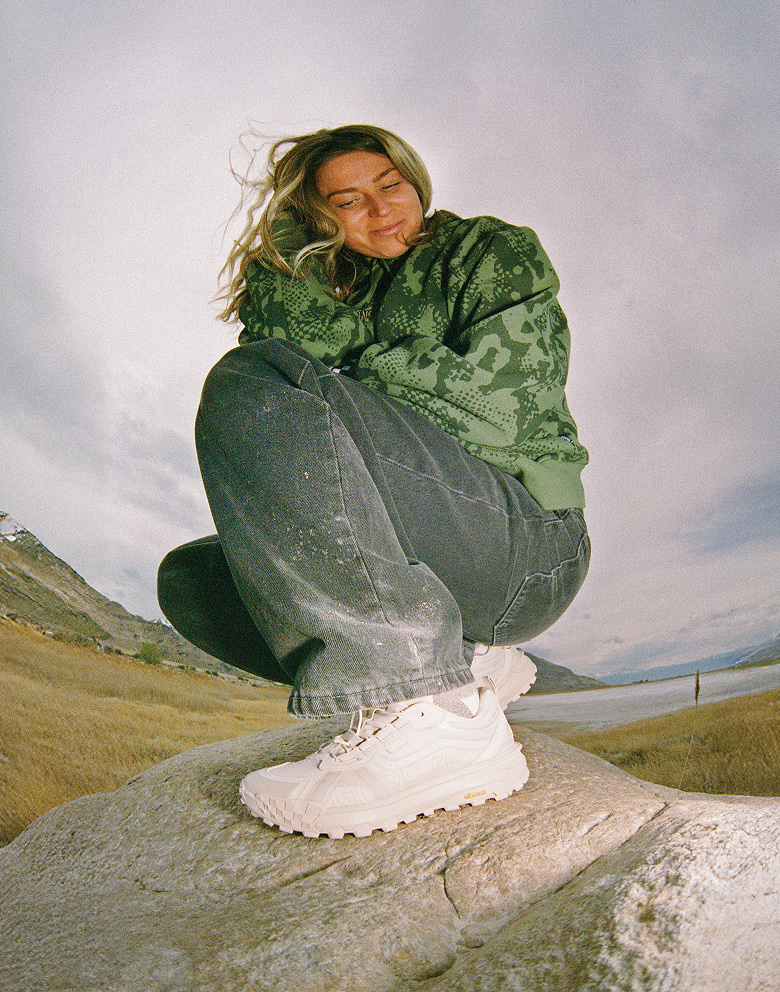 Woman outside standing on a rock showing off her Crosspath XC GORE-TEX Shoe in Marshmallow White.