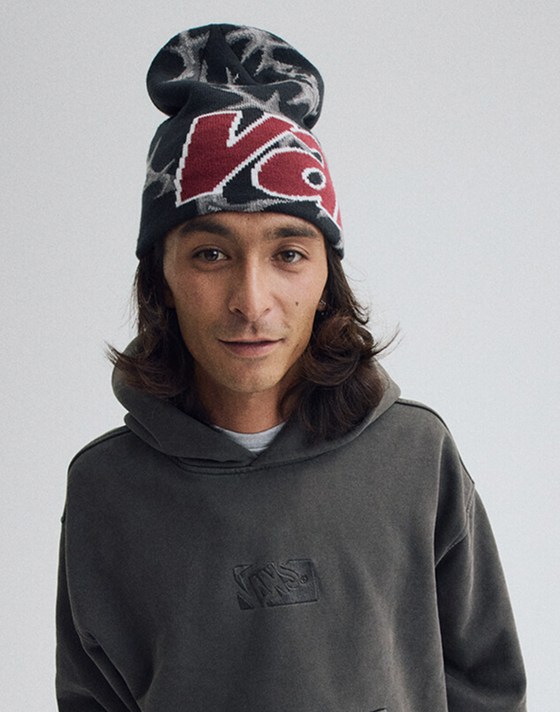 Image of a man wearing a Vans Skull Beanie in Faded Black. With a Premium Pullover Hoodie in Faded Black.