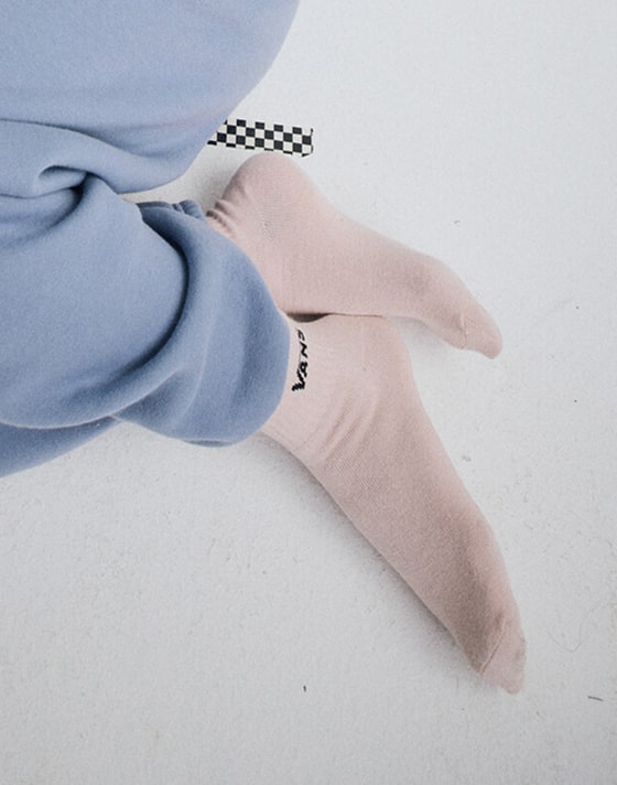 Person wearing pink Classic Half Crew Socks on the floor of a grey photography studio.