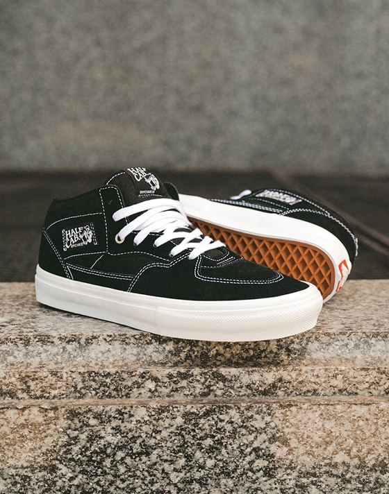 Image of a pair of black / white Skate Half Cab Shoe on the edge of a large town water fountain.