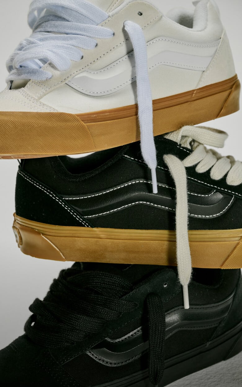 Three Knu Skool Shoes stacked on top of one another. Top is the Blanc De Blanc White, middle is the Gum Black, bottom is the Black.