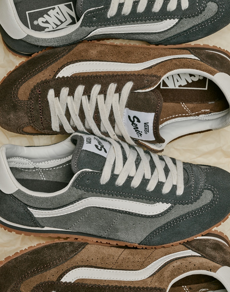 Alternating pairs Super Lowpro shoes in Demitasse Brown and Pewter Grey on the ground with a crumple paper background.
