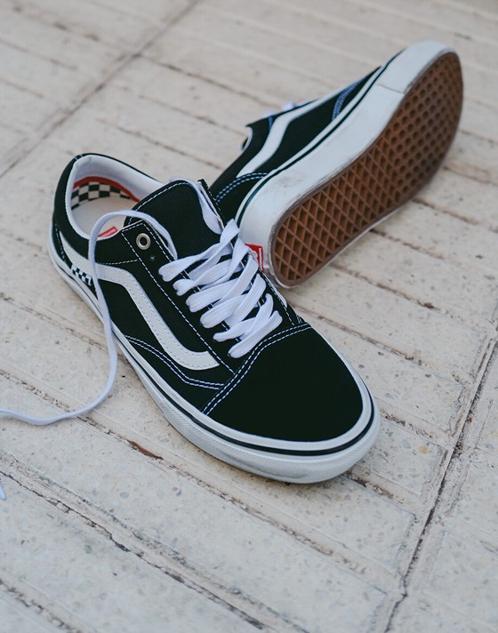 Image of a pair of the black / white Skate Old Skool Shoe sitting on the sidewalk with a couple of scuffs on them.