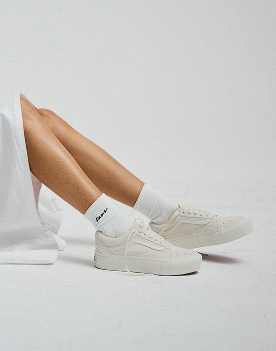 Wide shot from the knee down of someone sitting on the floor of a grey photography studio wearing the Old Skool Platform Shoe in Marshmallow White.