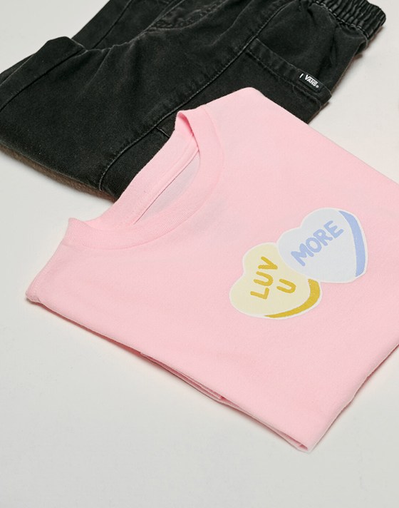Close up of the Kids Little Kids Candy Sweetheart T-Shirt in Coral Blush with a pari of Little Kids Naithin Denim Pants in Black next to it.