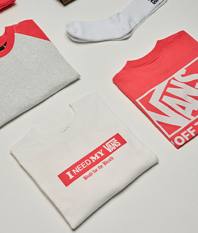 A variety of red and white t-shirts and socks folded and spread out on the floor of a photography studio from the Vans Valentine’s Day Collection.
