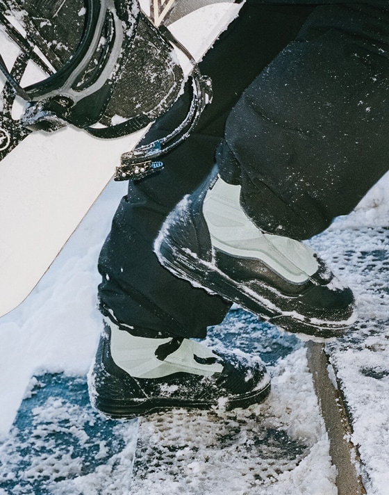 Close up of someone wearing a pair of the Infuse Snowboard Boot and climbing up snow covered stairs.