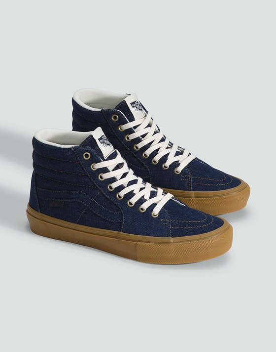 Medium shot of a pair of the Skate Sk8-Hi Shoe in Denim Blue on the floor of a grey photography studio.