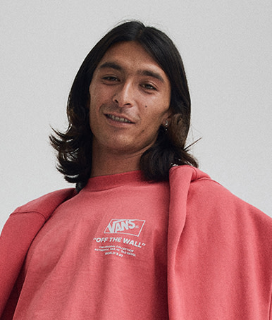 A young man poses in a photography studio wearing a crimson haze Stockpile T-Shirt and Premium Pullover Hoodie.