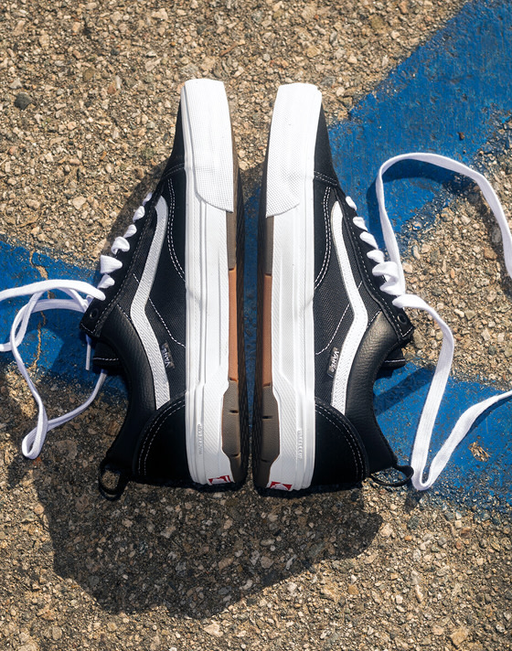 Medium shot of the Skate Old Skool WaffleCup in black and white laying with their soles facing each other on rocky pavement.