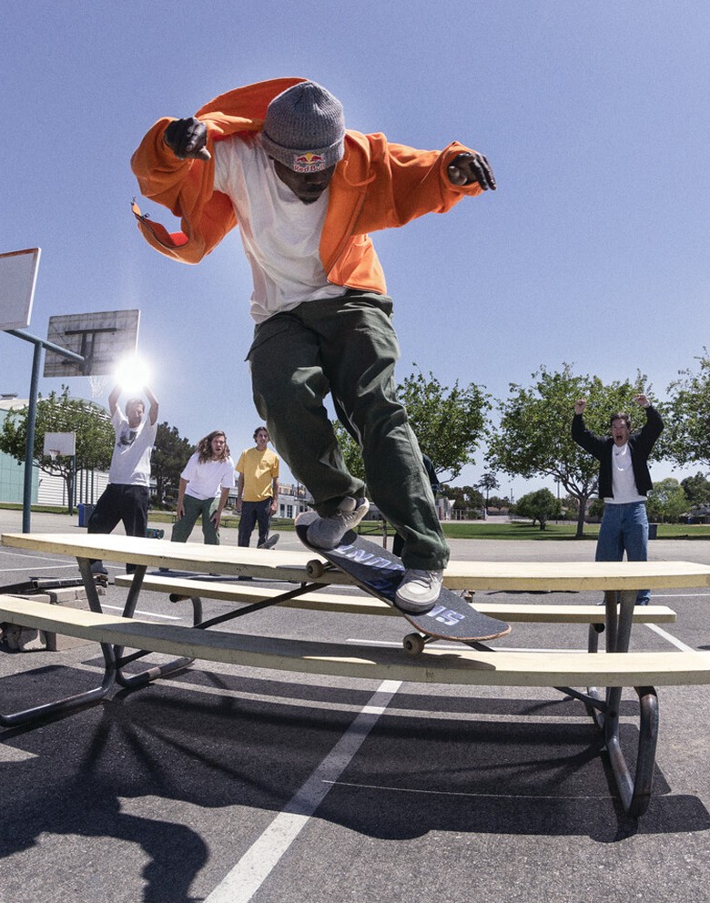 Fishbowl shot of a bunch of spectators cheering on a skateboarder Zion Wright grinding on a picnic table placed on the backside of a basketball court.