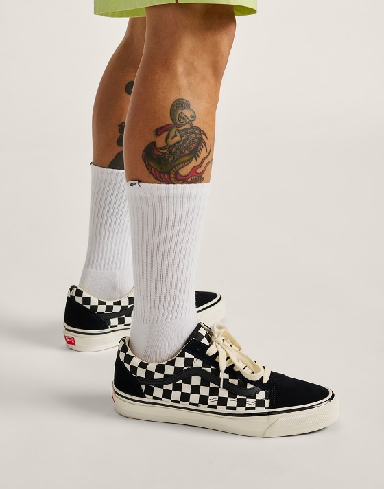 Knee down shot of a man wearing the Premium Old Skool Checkerboard in black and white with white Vans crew socks on.
