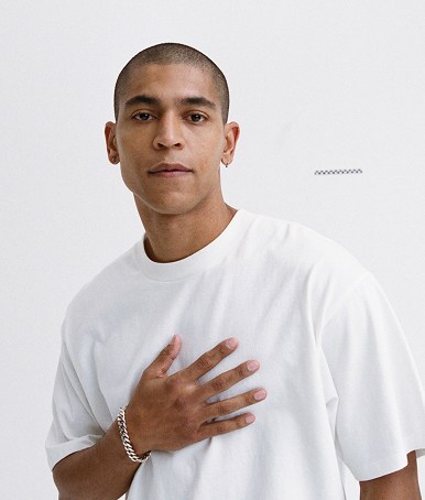 A young man poses in a photography studio wearing an egret white Premium Loose Fit T-Shirt.