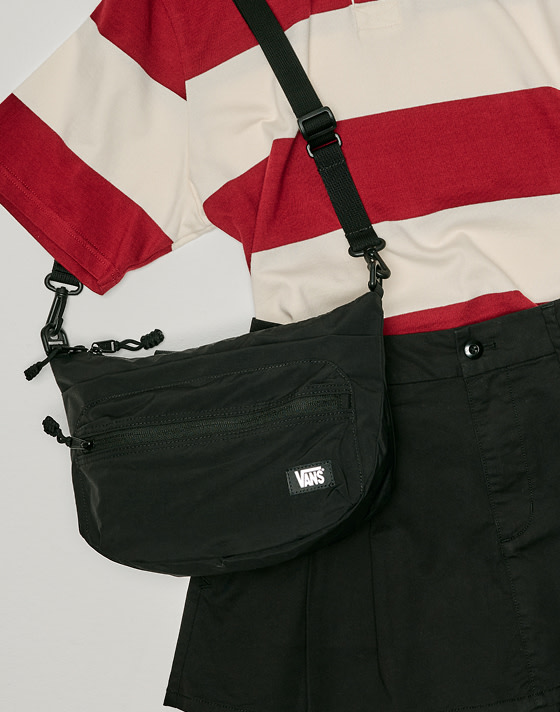 Top down shot of an outfit and a black Ward Ripstop Crossbody Bag on the floor of a grey photography studio﻿.