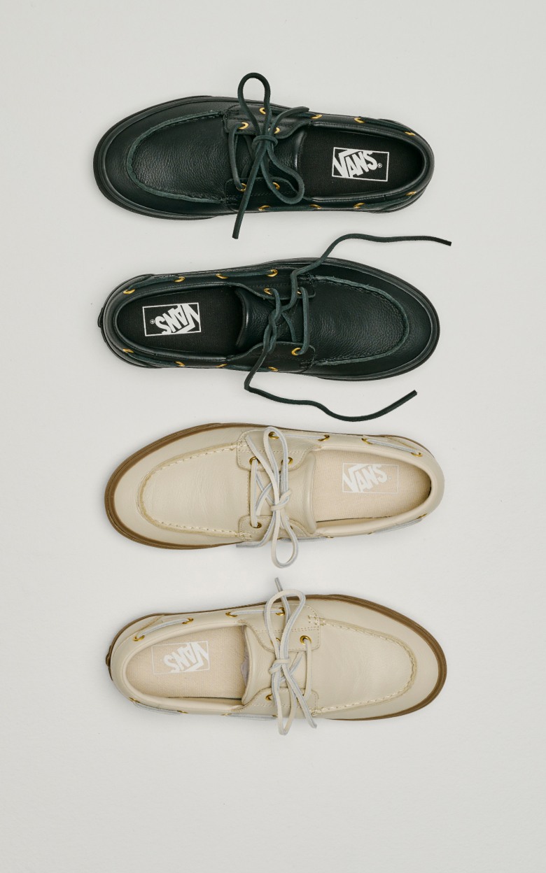 An overhead shot of the black colorway and cream colorway of the 2-Eyelet Boat Shoe on the floor of a photography studio.