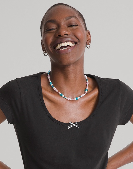 Close up shot of a woman smiling and wearing a black Checkerboard Bow Scoop T-Shirt.