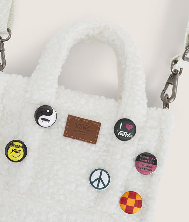 Close up of a Fleece Marshmallow White Lil Pergs Tote Bag with pins decorating it.
