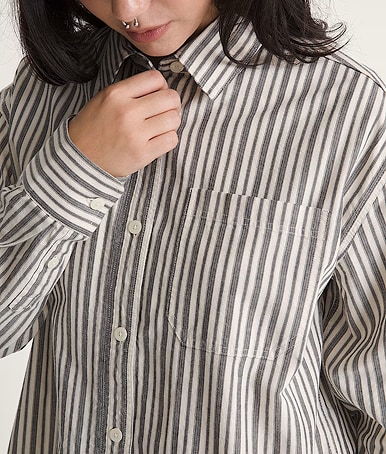 Close up of a woman wearing a brown and white vertically striped long sleeve button up.