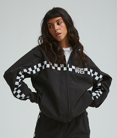 Plan à partir de la taille montrant une jeune femme portant le blouson de sport Ronnie en noir dans un studio photo.