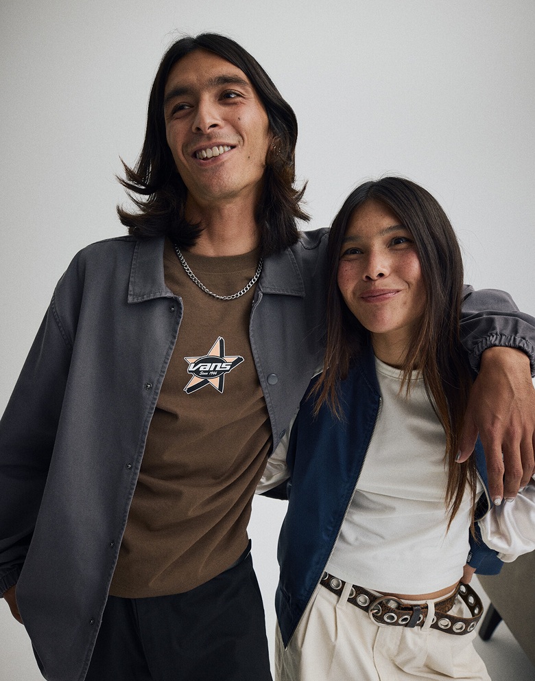 Plan moyen à partir de la taille montrant un homme qui a le bras autour des épaules d’une femme. Il porte une veste de style entraîneur en toile Torrey Pigment, elle porte une veste Souvenir.