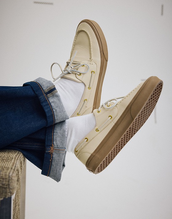 Close up of a man wearing a pair of the Tan Brown 2-Eyelet Boat Shoe and kicking his feet up on the end of a couch.