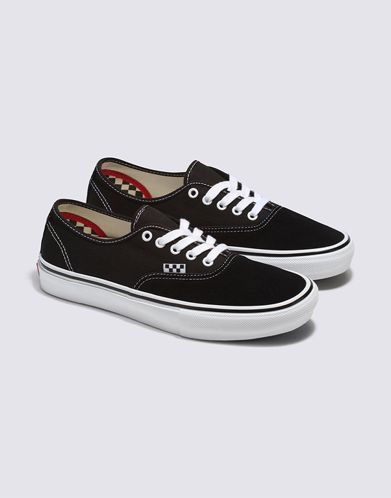 Medium shot of a pair of the Black / White Skate Authentic Shoe on the floor of a grey photography studio.