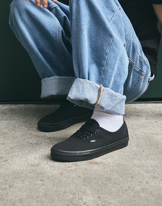 Knee down close up of someone squatting outside on the pavement wearing a pair of the Blackout Authentic Shoe.