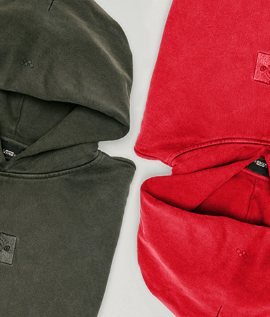 A pair of faded black and crimson haze red Premium Pullover Hoodies on the floor of a photography studio.