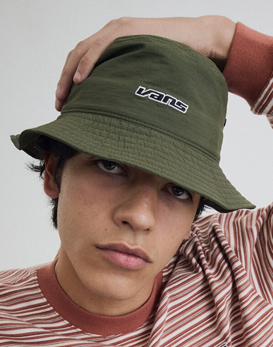 Close-up on a young man wearing a green Dropped V Bucket Hat in a photography studio.
