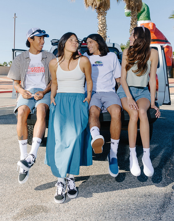 A group of friends on a truck bed under palm trees wearing Vans shoes and clothes for spring break.