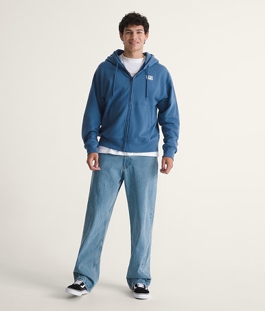 Un jeune homme porte un jeans Check-5 à coupe ample et des Authentic dans un studio photo.