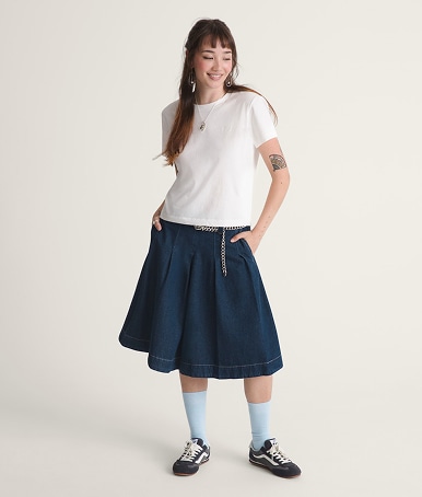 Une jeune femme pose dans un studio photo. Elle porte le Authentic à motif en damier rose et bleu marine et une jupe longue Francesca bleue.